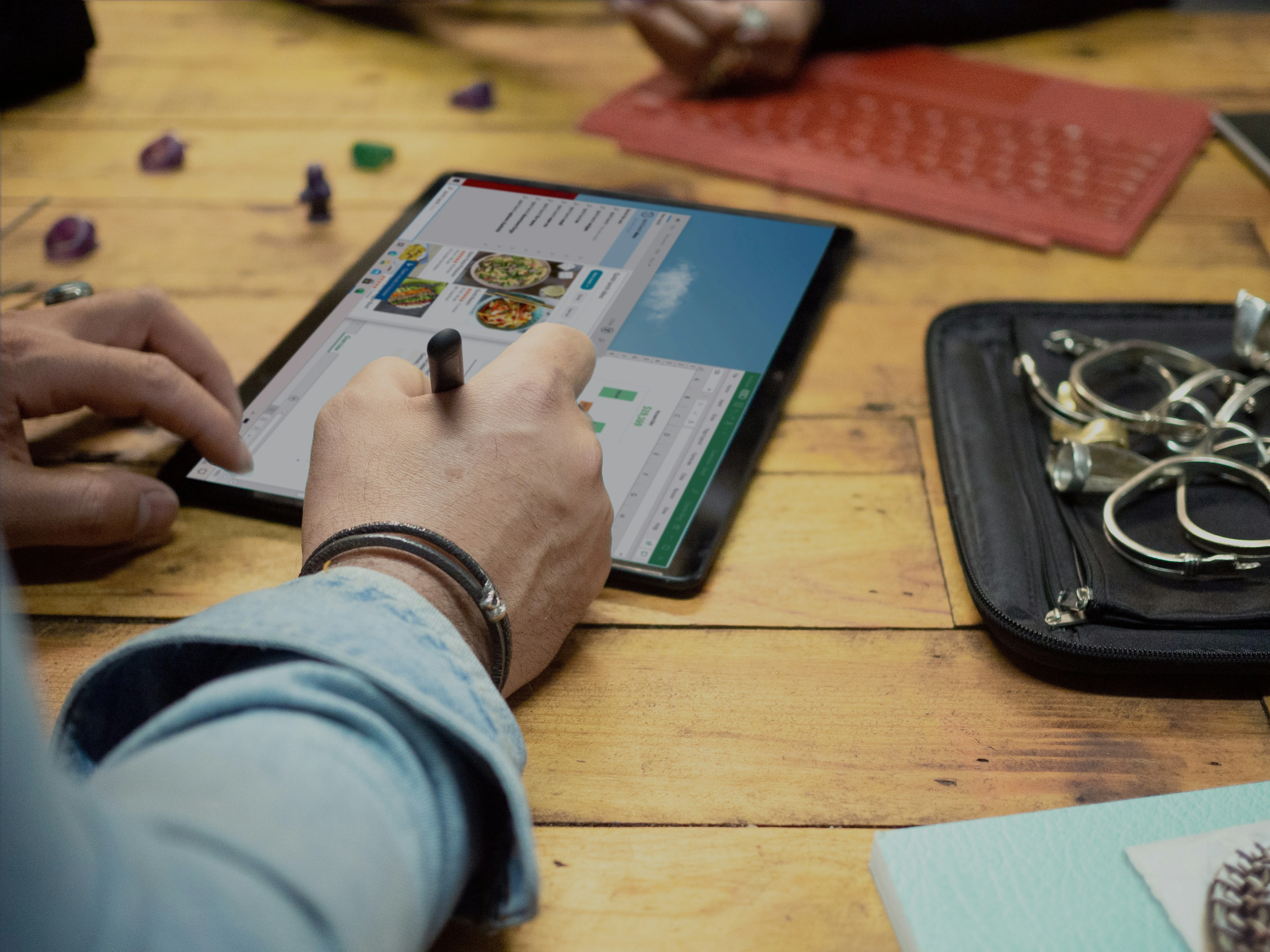 A gaming table with notebooks, a laptop, phone, and polyhedral dice — the tools DMs use to take campaign notes